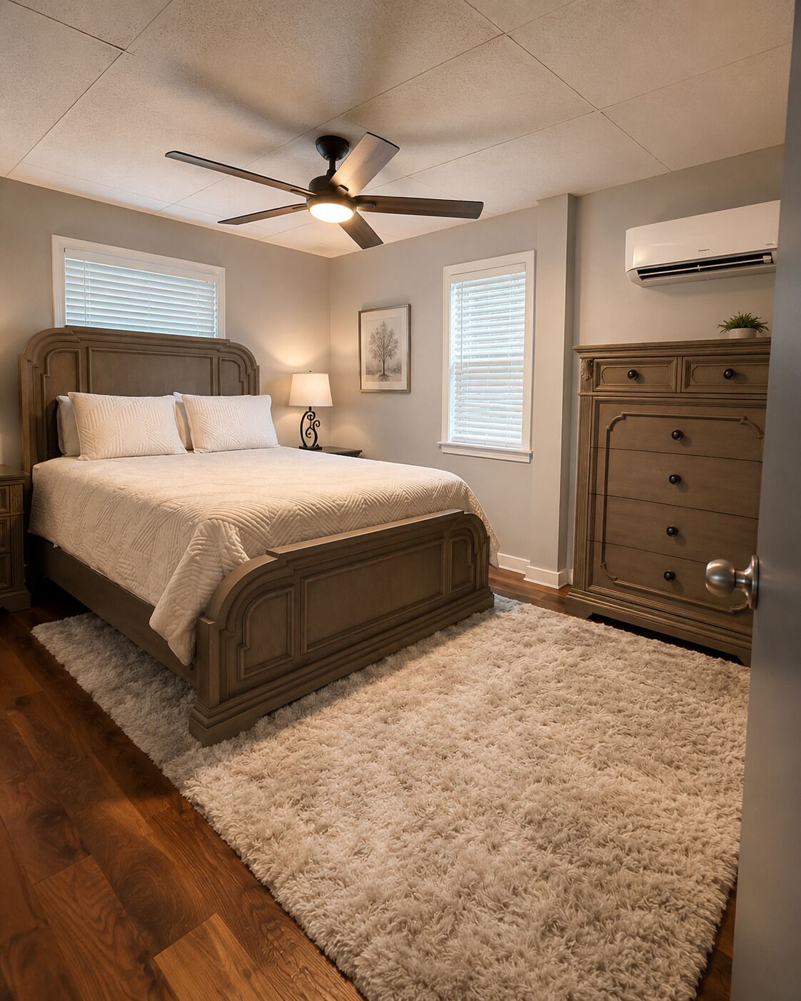 A bedroom with a bed, a ceiling fan, a dresser, and a window with blinds.