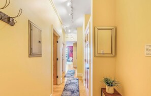 A hotel hallway with a wooden floor, a patterned rug, a mirror, and a potted plant. - The Asheville Jewel Downtown Asheville 1BR with queen bed, full kitchen, Wi-Fi, and elevator. (Asheville)