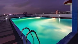 Piscina no terraço com vista desobstruída do horizonte urbano ao entardecer.