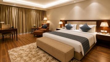 Ein Hotelzimmer mit einem großen Bett, zwei Nachttischen, einem Sessel, einem Schreibtisch und einem Teppichboden.