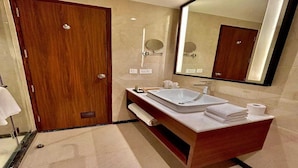 Uma casa de banho moderna com porta de madeira, um espelho grande, toucador com lavatório e um porta-toalhas.