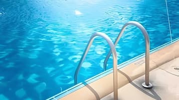 Ein Swimmingpool mit klarem, blauen Wasser und Metallleiter.