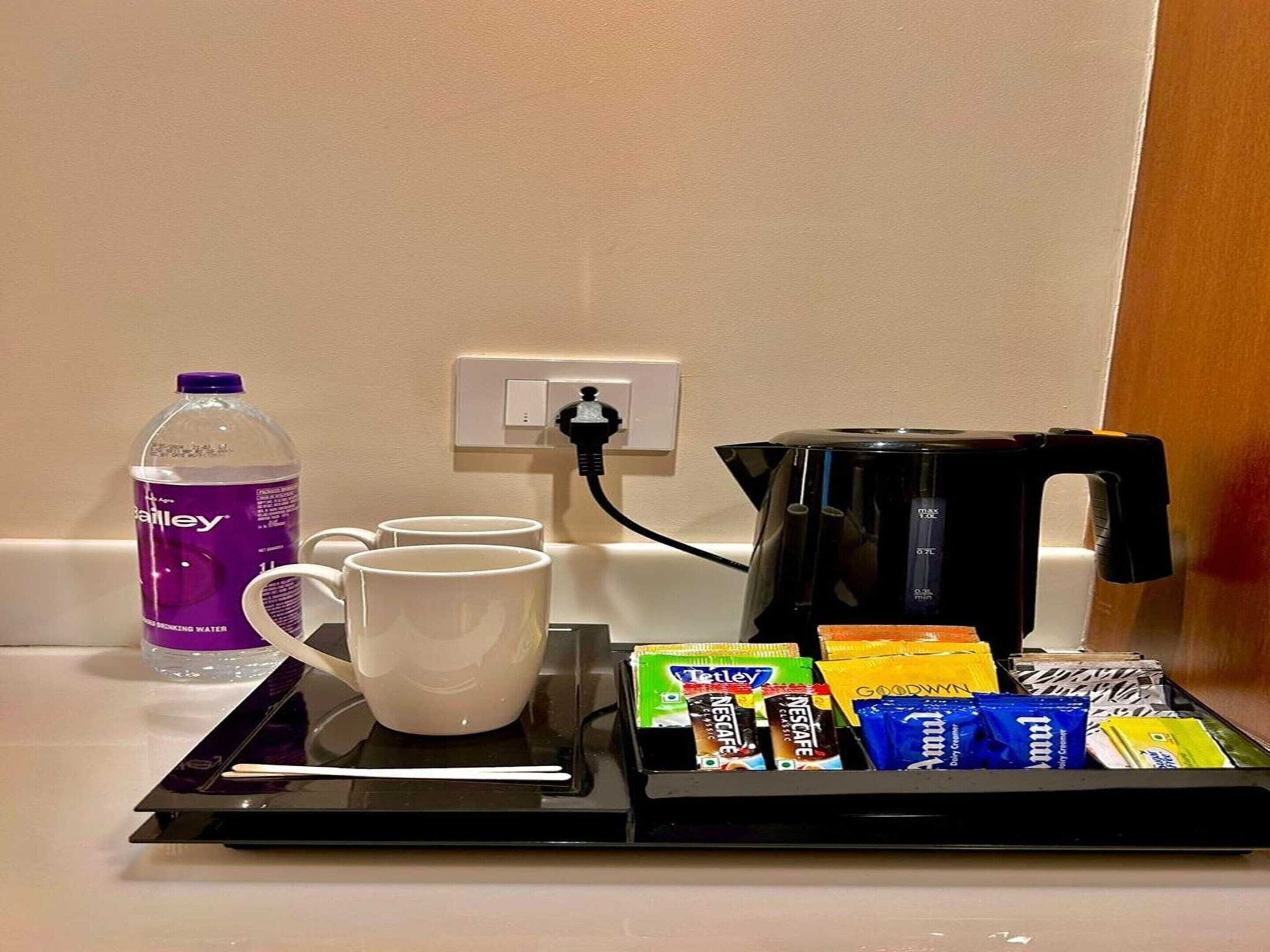 A hotel room's breakfast setup with a water bottle, coffee maker, and assorted coffee pods.