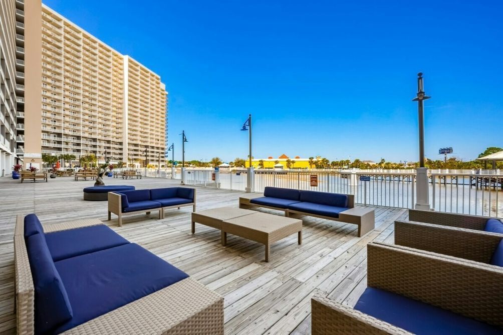 Una terraza de madera con mobiliario exterior azul y beige, con vistas a un paisaje urbano con edificios altos.