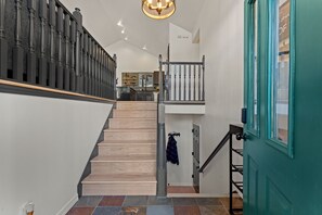 A staircase with wooden steps and a metal railing, leading to a landing with a view of a kitchen area. - Private Mountain Retreat w/Hot Tub & Game Room I Sleeps 12 (Woodland Park)