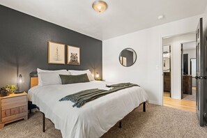 A bedroom with a bed, bedside tables, a mirror, and artwork on the wall. - Private Mountain Retreat w/Hot Tub & Game Room I Sleeps 12 (Woodland Park)