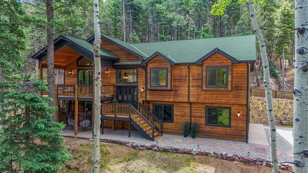 Une cabane en rondins à plusieurs niveaux, dotée d’un balcon et entourée d’arbres.