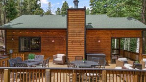 Une cabane dotée d’une terrasse, de meubles de jardin et d’une cheminée.