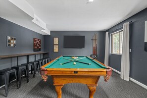 A pool table in a room with grey walls, a flat-screen TV, and a window with curtains. - Private Mountain Retreat w/Hot Tub & Game Room I Sleeps 12 (Woodland Park)