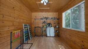 Een houten kamer met een raam, een plafondventilator en sportartikelen zoals rackets en een volleybal.