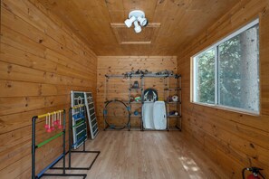 Una habitación de madera con ventana y ventilador de techo, con equipo deportivo como raquetas y voleibol.