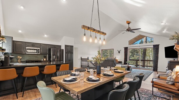 Een ruime keuken met moderne apparatuur, een eetgedeelte met een houten tafel en stoelen, en een groot raam met uitzicht op de omgeving.