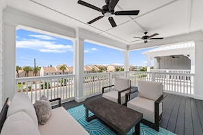 A covered outdoor seating area with white railings, a ceiling fan, and a view of a residential neighborhood. - BeachVillaII-14G, ArcadeGames,5B/4.5B, Priv H/C Pool,2Min2Beach,Deck&Gulf views (Panama City)