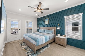 Ett sovrum med en säng, sängbord, en takfläkt och ett fönster med persienner.