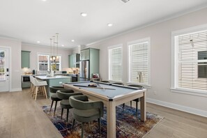 A modern kitchen with a central island, bar stools, and a pool table. - BeachVillaII-14G, ArcadeGames,5B/4.5B, Priv H/C Pool,2Min2Beach,Deck&Gulf views (Panama City)