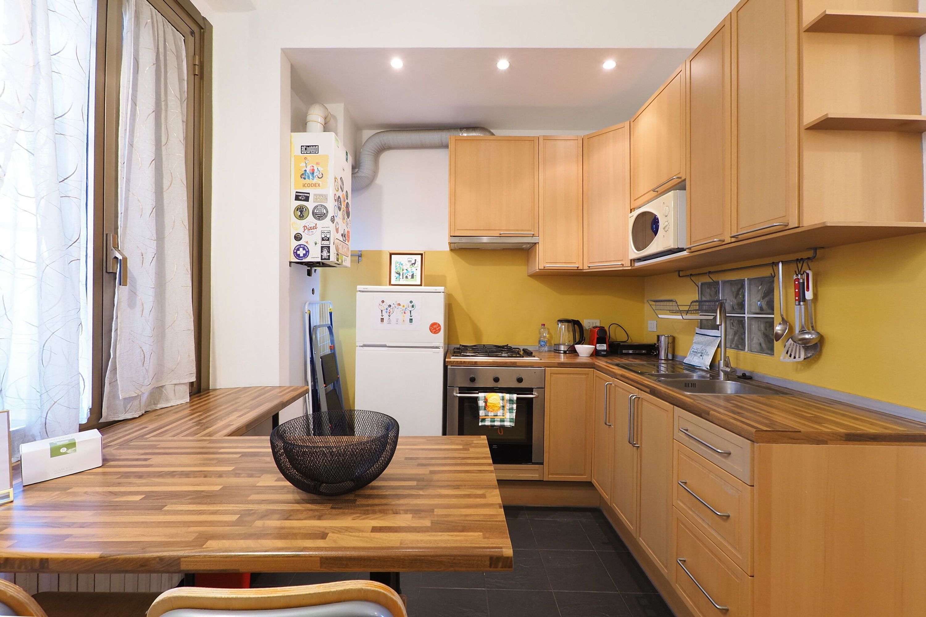A compact kitchen with wooden cabinets, a microwave, a gas stove, and a refrigerator.