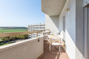 A balcony with a table and chairs, overlooking a green landscape and a building in the distance. - Suite Riviera in Porto Recanati (Porto Recanati)