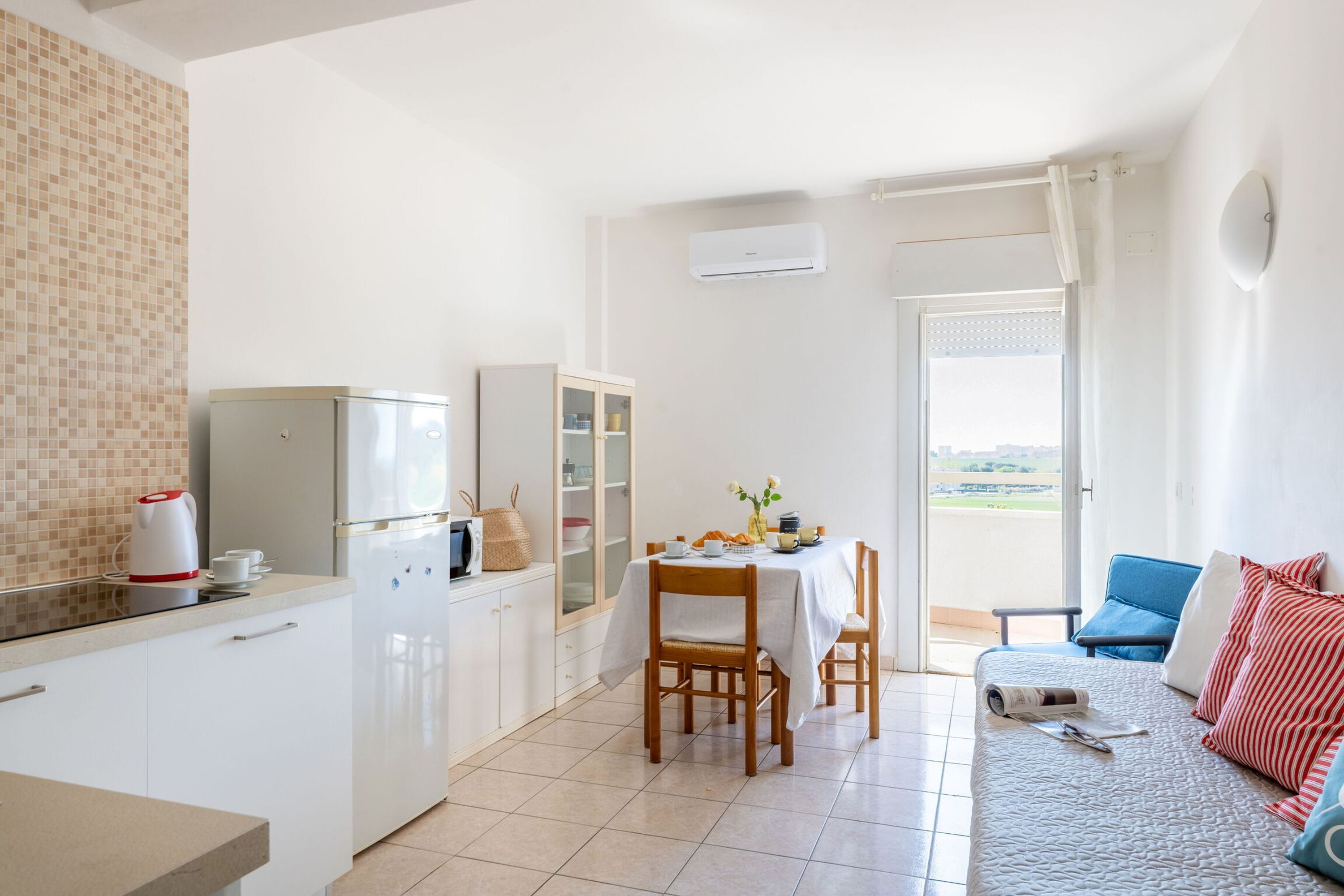 A compact living space with a kitchenette, dining area, and a sofa with a view.