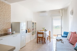 A compact living space with a kitchenette, dining area, and a sofa with a view. - Suite Riviera in Porto Recanati (Porto Recanati)