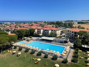 A resort with a large swimming pool, multiple buildings with red roofs, and a clear view of the sea. - Suite Riviera in Porto Recanati (Porto Recanati)