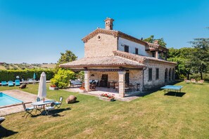 A two-story house with a brick facade, a patio with outdoor furniture, and a swimming pool. - Villa Incanto in Potenza Picena (Potenza Picena)