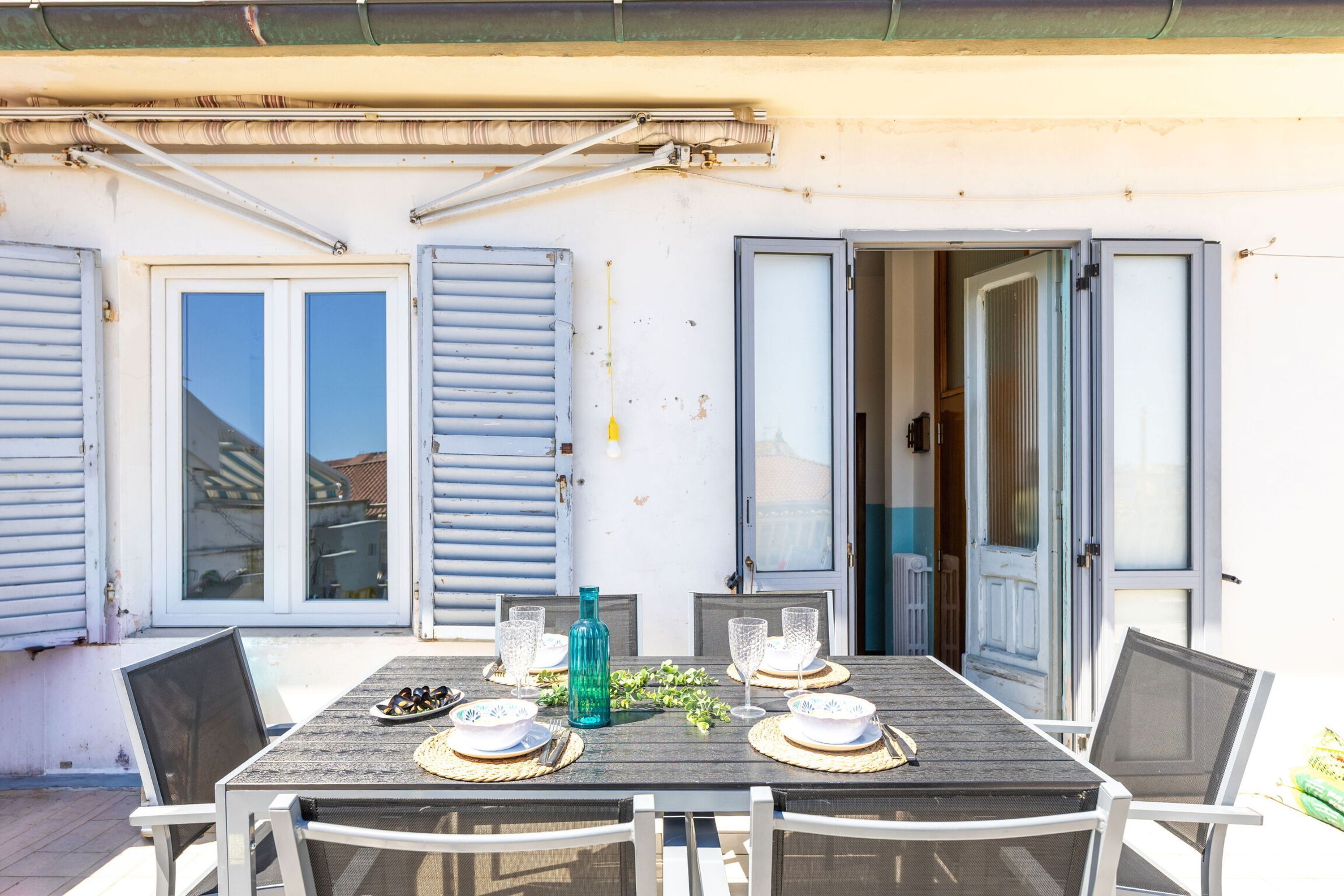 An outdoor dining area with a table set for four, surrounded by chairs.