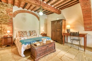 Una habitación tradicional con cama, muebles de madera y suelo de piedra.