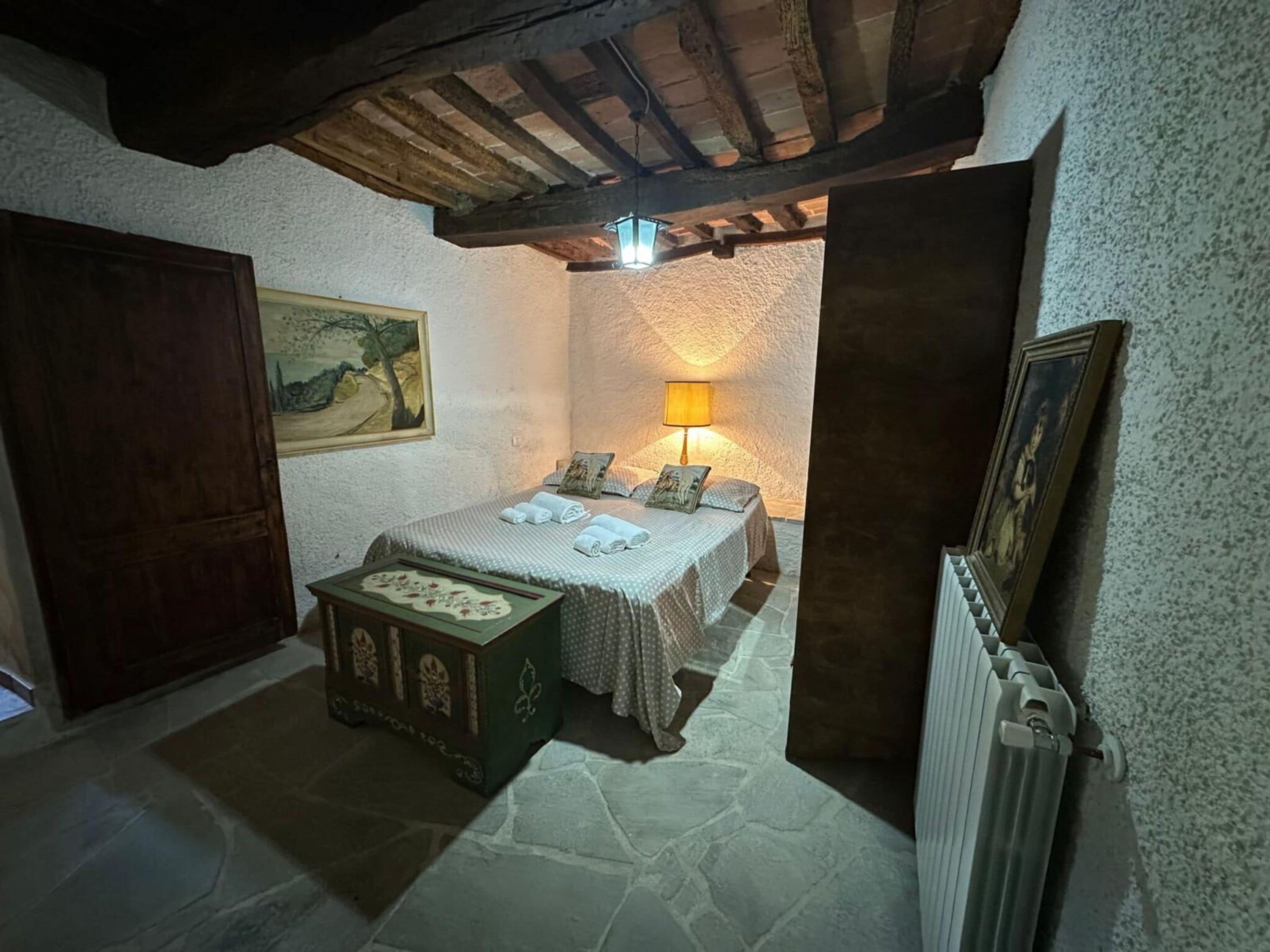 A bedroom with a bed, a nightstand, a lamp, and a painting on the wall.