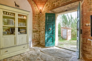 Un interior rústico con una pared de piedra, una puerta verde y un mueble con puertas de cristal.