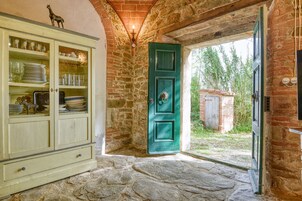 Un interior rústico con una pared de piedra, una puerta verde y un mueble con puertas de cristal.