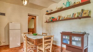 Una cocina compacta con una mesa de comedor, sillas, un refrigerador y un armario con estantes superiores.