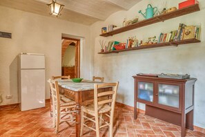 Una cocina compacta con una mesa de comedor, sillas, un refrigerador y un armario con estantes superiores.