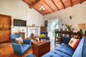 Amplia sala de estar con techo alto, chimenea, televisor y vistas al exterior.