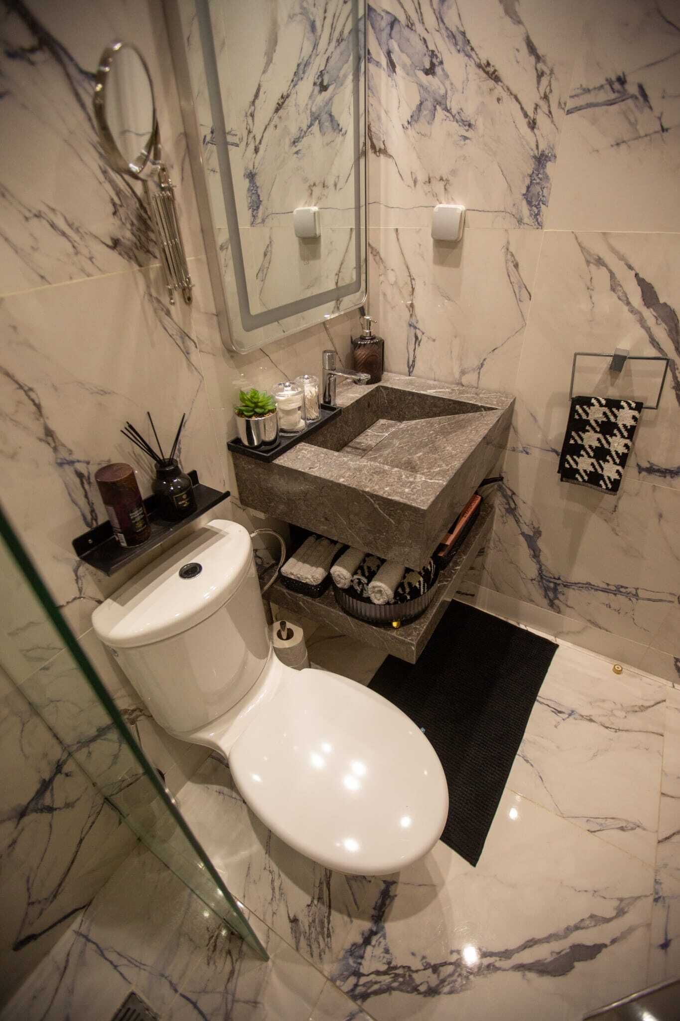 A bathroom with a marble sink, a toilet, and a glass shower enclosure.