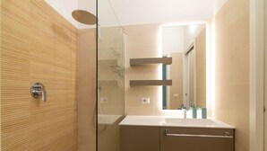 A modern bathroom with a glass shower enclosure, a white sink, and a mirror.