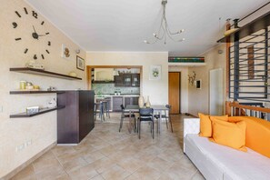 A modern living room with a sofa, dining table, and kitchen area. - Casa Dolceconero in Castelfidardo (Castelfidardo)