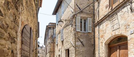A narrow street with stone buildings, wooden doors, and shutters.