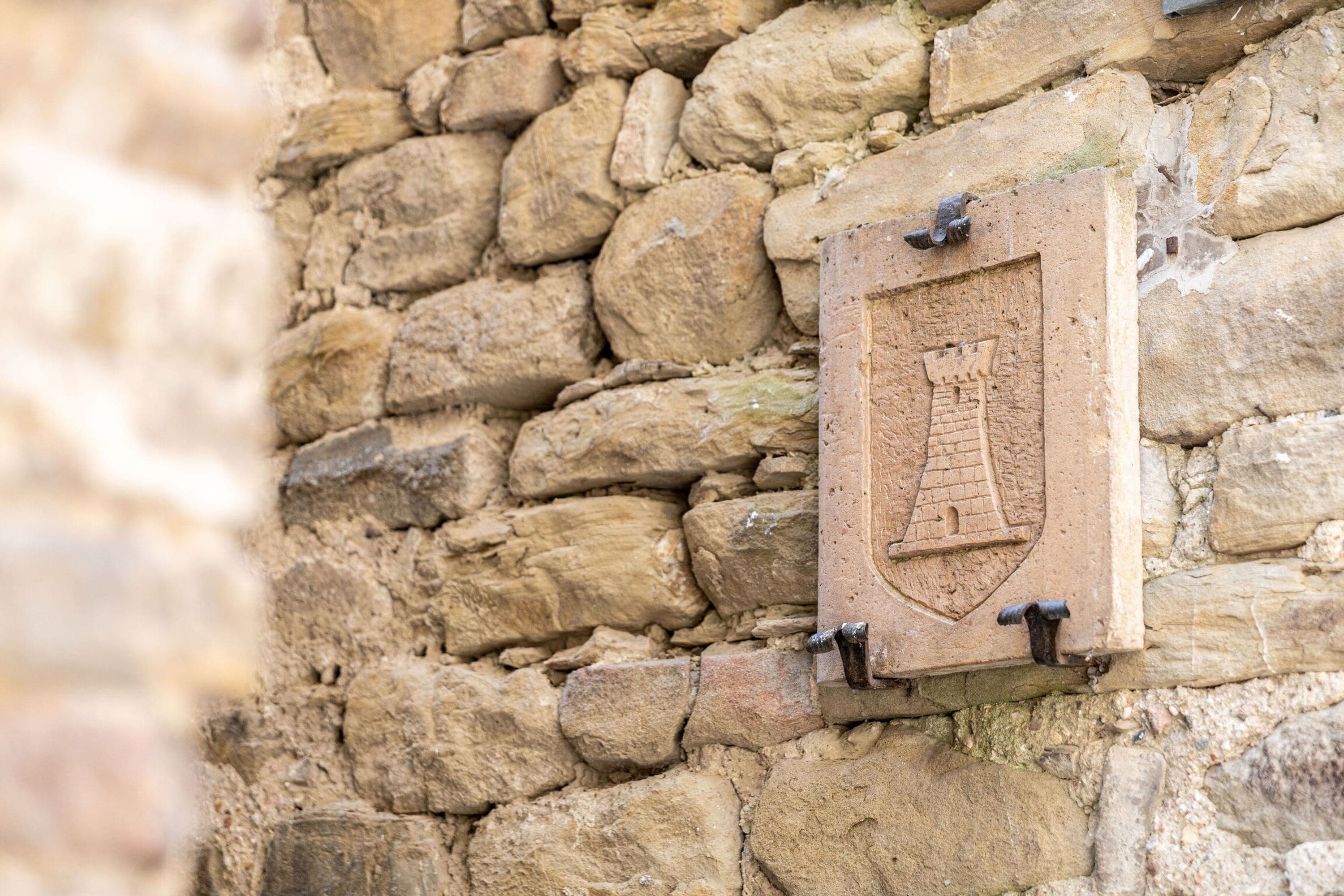 A stone wall with a plaque featuring a ship and anchor emblem.