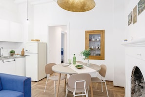A modern kitchen with white cabinets, a built-in refrigerator, and a dining area with a round table and chairs. - Suite Sinfonia Blu in Bevagna (Bevagna)