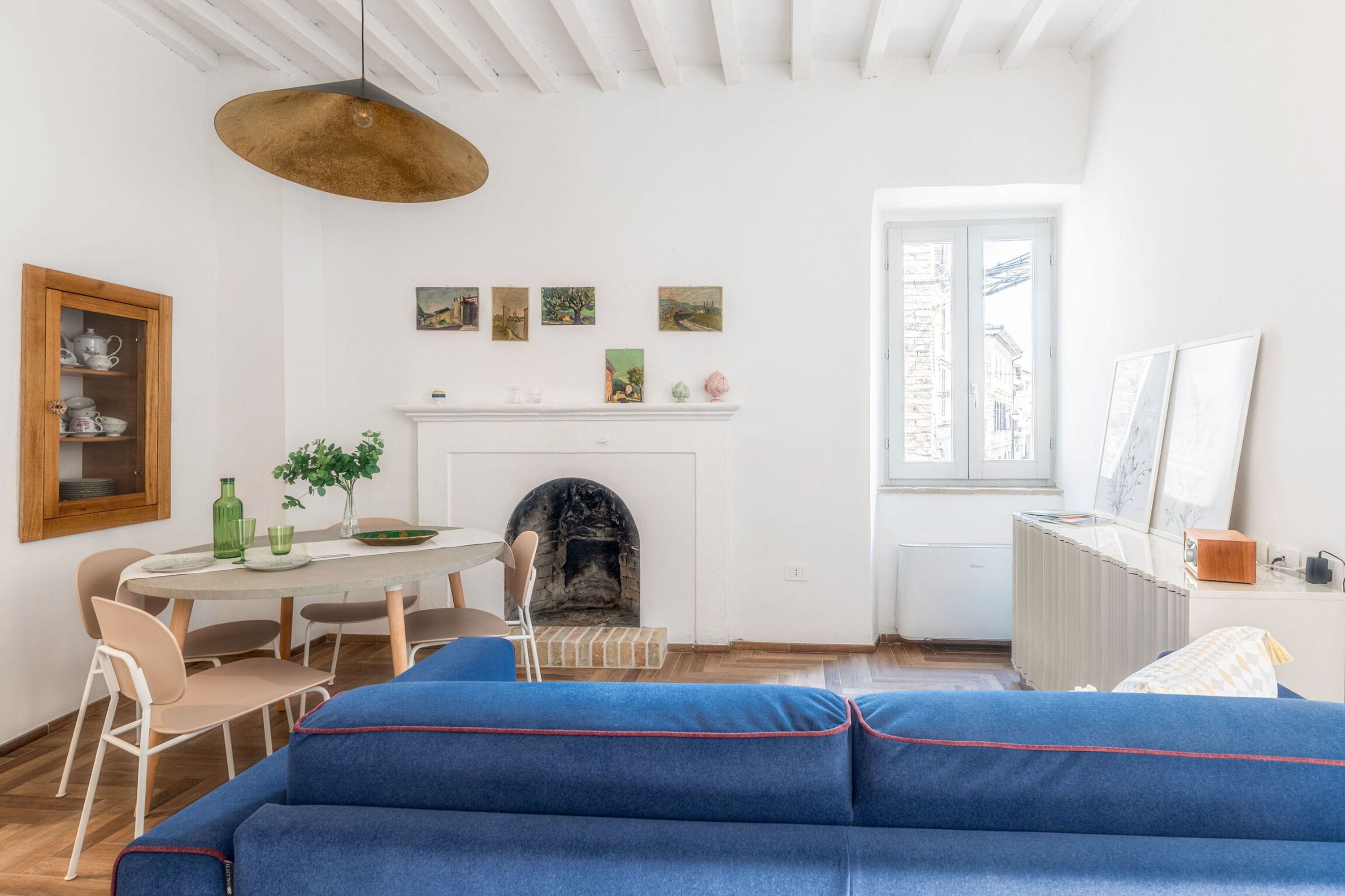 A room with a fireplace, dining table, and a sofa.