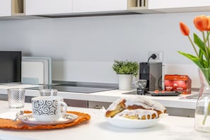 Cozinha moderna com área de jantar, incluindo cafeteira, planta e um prato de comida.