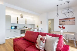 Uma sala de estar moderna com um sofá vermelho, uma área de cozinha e um espaço para refeições.
