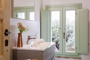 A bathroom with a sink, mirror, and a window with a view of trees. - Zena Suite in Cingoli (Cupramontana)