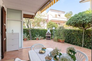 A patio with a table set for dining, surrounded by potted plants and a barbecue grill. - Veranda sul Conero in Marcelli (Numana)