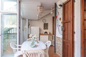 A dining area with a table set for two, a white chair, a vase with flowers, and a clock on the wall. - Veranda sul Conero in Marcelli (Numana)