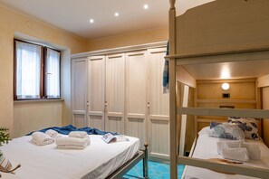 A hotel room with bunk beds, a wardrobe, a window with curtains, and a bedside table with a lamp. - Suite la Torre in Numana (Numana)