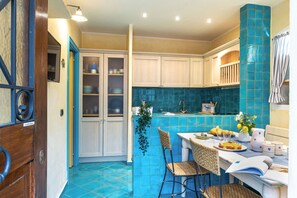 A kitchen with a dining area, featuring a blue tiled backsplash, wooden cabinets, and a dining table with chairs. - Suite la Torre in Numana (Numana)