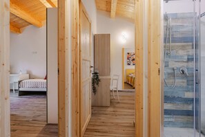 A modern interior with a wooden floor, a bed, a desk, and a shower area. - Zena Apartment in Cingoli (Cupramontana)