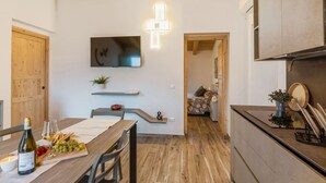 Ett modernt kök med träbjälkar, en matplats med ett bord dukat för en måltid och en tv som är monterad på väggen.