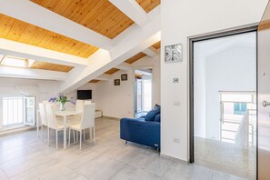 A modern interior with a dining area, a sofa, and a large window. - Seaside Apartment in Porto Potenza Picena (Potenza Picena)